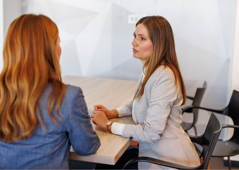 Two women having a discussion at table.