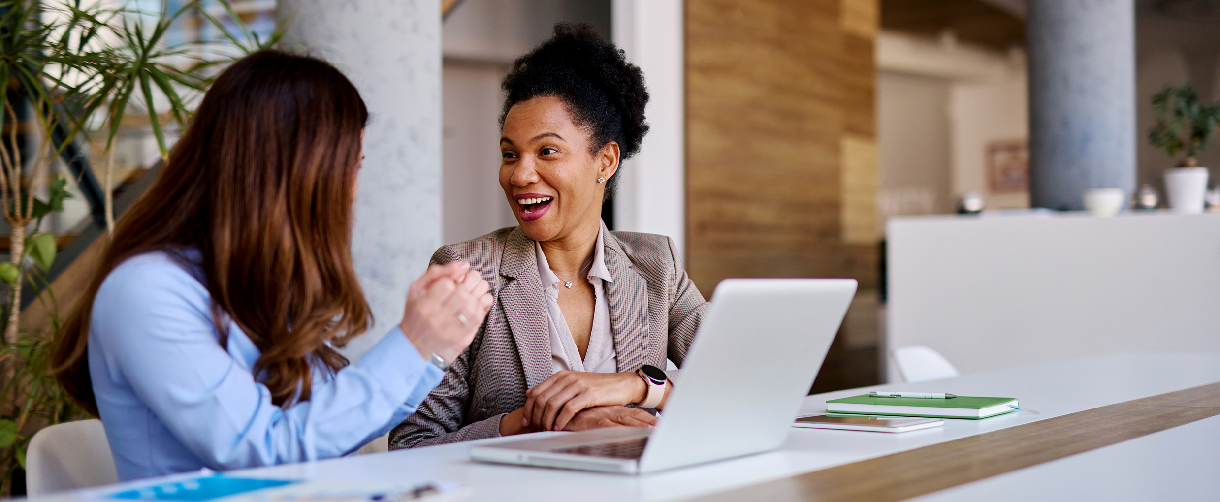 Two women happily conversing in an office.
